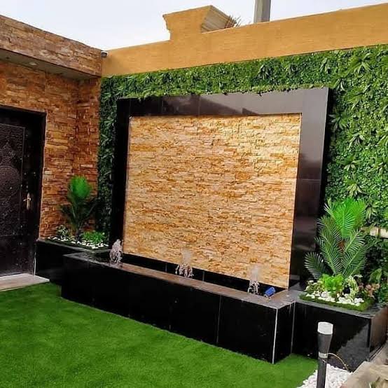 شلال صخري طبيعي شلال حجري طبيعي بواجهة حجر جبلي وحوض أسود مع جدار زرع صناعي