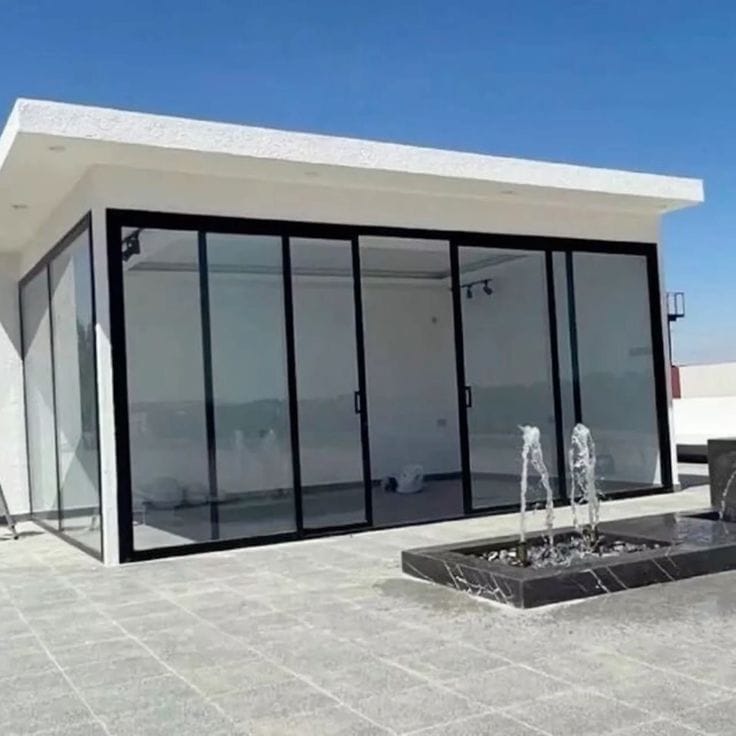 غرفة زجاجية بيضاء بواجهة زجاجية كاملة ونافورة أمامية