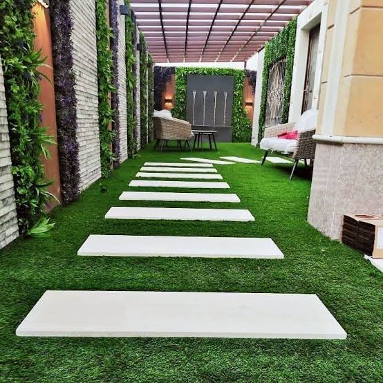 جلسة خارجية تحت برجولة خشبية مع جدران خضراء
